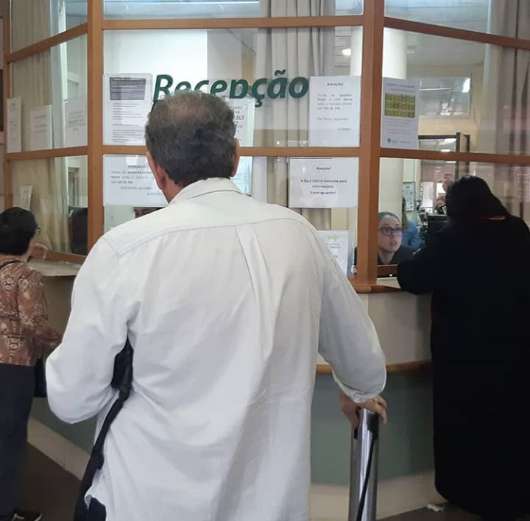 Pacientes fazem fila para atendimento médico na recepção. 